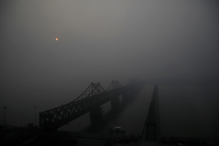 The sun struggles to penetrate the smog over the Friendship and the Broken bridges connecting Sinuiju and Dandong. (Damir Sagolj / Reuters)